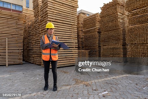 A female warehouse worker works in an open-air timber warehouse