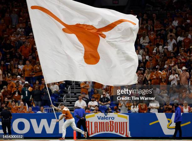 Texas Longhorns cheerleader runs with a flag in the second half against the Washington Huskies during the Valero Alamo Bowl at Alamodome on December...
