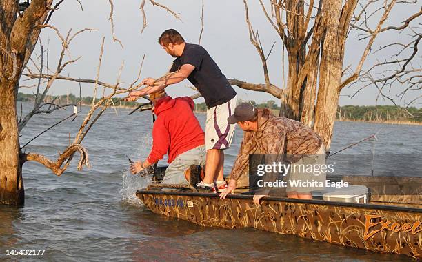 Flathead catfish jumps as Darrell Conrade, left, checks the line on a Topcat at El Dorado Reservoir in Kansas.