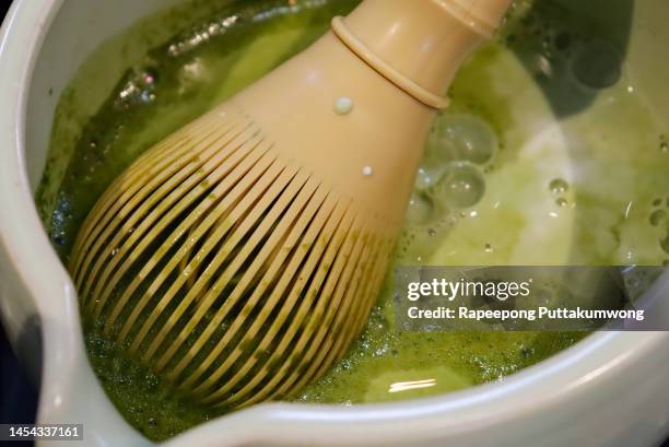 close-up of tea cup and tea whisk on table making, stirring and preparing koicha matcha hot drink - powder tea stock pictures, royalty-free photos & images