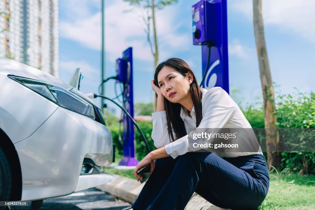 Impatient woman charging car at station.