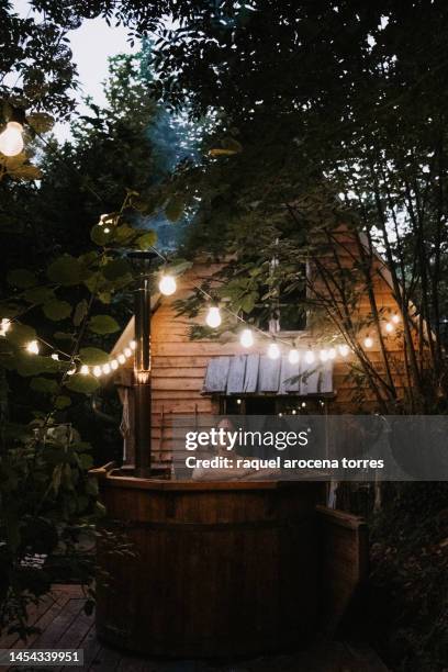 adult woman taking a bath in a nordic bathtub next to a wooden cabin - idyllic cottage stock pictures, royalty-free photos & images
