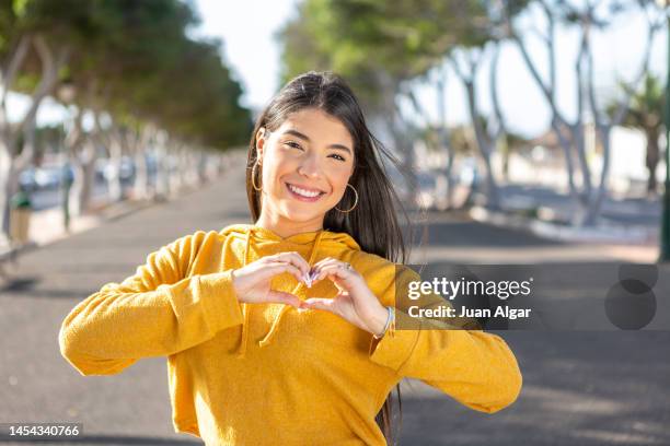 smiling teen girl showing love sign - truehearts stock pictures, royalty-free photos & images