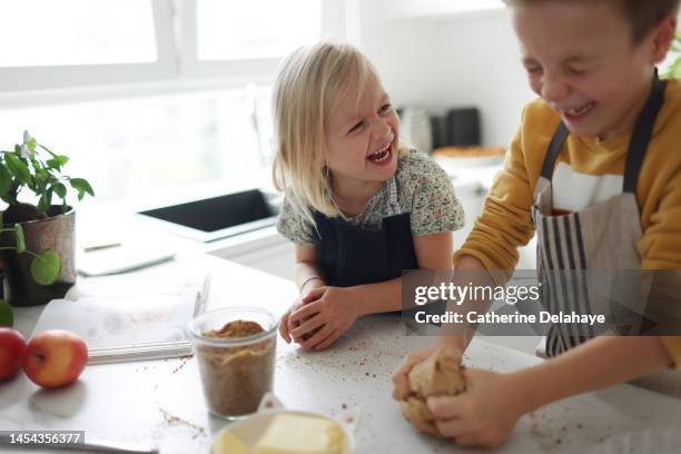 a brother and a sister laughing together as they preparing a apple pie in the kitchen - bruder schwester kochen stock-fotos und bilder