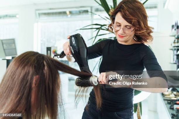 hair drying and combing female customer hair. stylish hairdresser cutting and drying woman hair in salon - cabeleireiro imagens e fotografias de stock