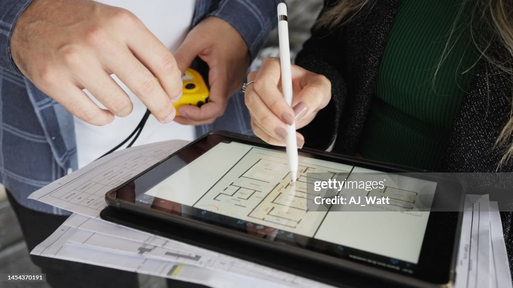 Close-up de dois arquitetos trabalhando em tablet digital no escritório