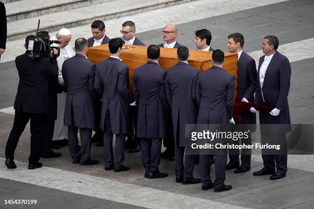 Pope Francis touches the coffin of Pope Emeritus Benedict XVI as pallbearers carry it towards St Peter’s Basilica for the burial after the funeral...