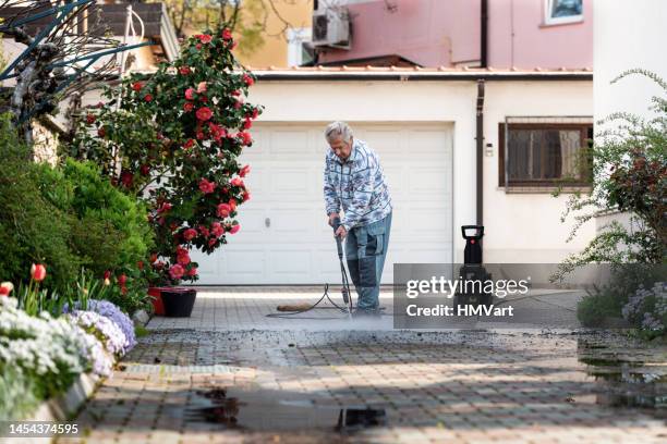 senior mann zu hause reinigung des hofes mit hochdruckreiniger - person holding flowers with high energy stock-fotos und bilder