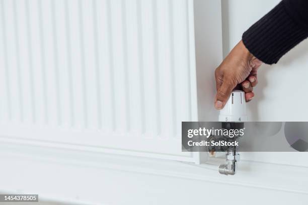 adjusting the heating temperature - heating home stock pictures, royalty-free photos & images