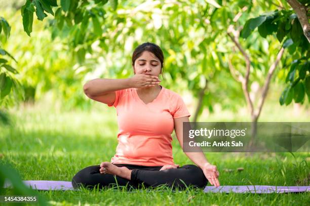 woman practices pranayama or breathing exercise while sitting in lotus pose - namaste greeting stock pictures, royalty-free photos & images