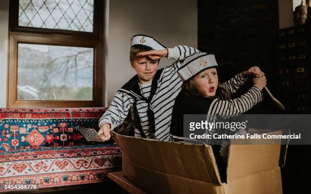 two children sit in a large box, wearing nautical costumes, pretending to be sailors - animal related occupation stock pictures, royalty-free photos & images