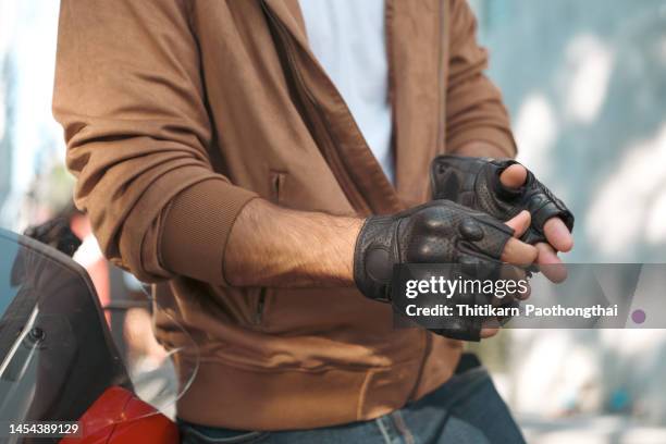 close up young businessman taking of motorcycle glove. - motociclista fotografías e imágenes de stock