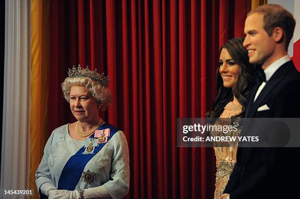 New waxwork statue of Britain's Queen Elizabeth II stands next to a statue of Catherine, Duchess of Cambridge and Prince William as children from...