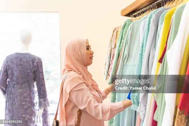 asian woman looking at various clothes at fashion store - anständig klädsel bildbanksfoton och bilder