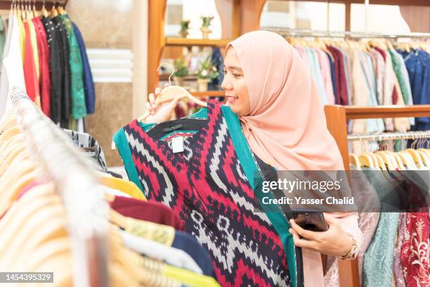 asian woman trying on dress with indonesia traditional design - batik dress stock pictures, royalty-free photos & images