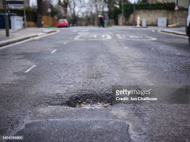 a large pot hole on residential street in north london - london road stock pictures, royalty-free photos & images