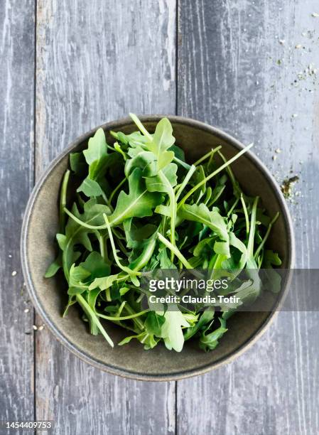 bowl of arugula on wooden, gray background - arugula stock pictures, royalty-free photos & images