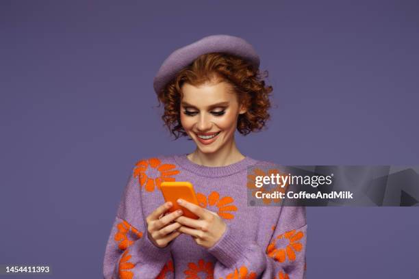 beautiful emotional woman using smartphone - purple hat stock pictures, royalty-free photos & images