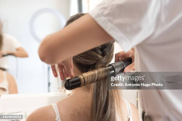 close up of a hairdresser straightening the hair with a flat iron to client. hairdressing session. - quarantine wedding stock pictures, royalty-free photos & images
