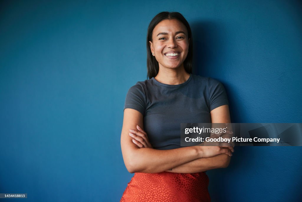 Young businesswoman smiling while standing against a blue backdrop