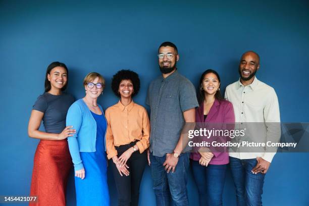 lächelnde gruppe verschiedener geschäftsleute vor blauem hintergrund - business group portrait stock-fotos und bilder