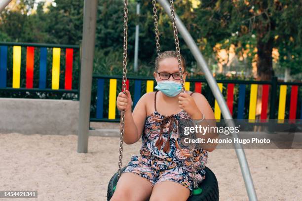 blonde girl with face mask swinging on the park - child obesity stock pictures, royalty-free photos & images