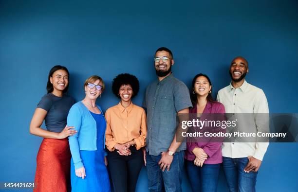 laughing group of diverse businesspeople standing against a blue background - business portrait laughing studio stock pictures, royalty-free photos & images