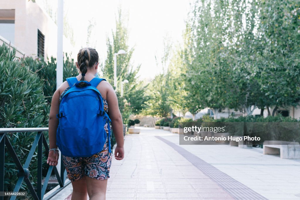 Blonde girl with blue backpack on her way to school