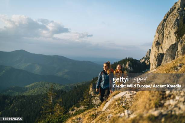 hikers ascend mountain slope above valley - escape rom stock pictures, royalty-free photos & images