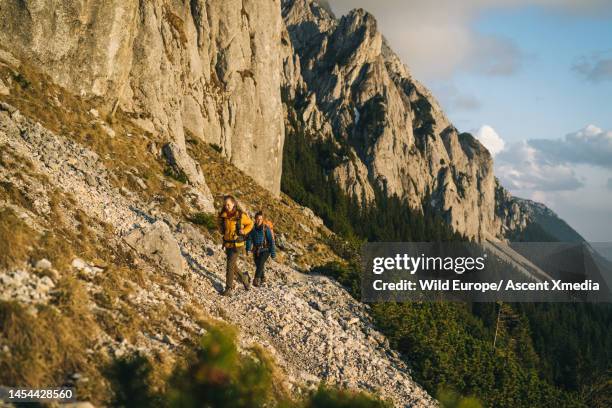 hikers ascend mountain slope above valley - escape rom stock pictures, royalty-free photos & images