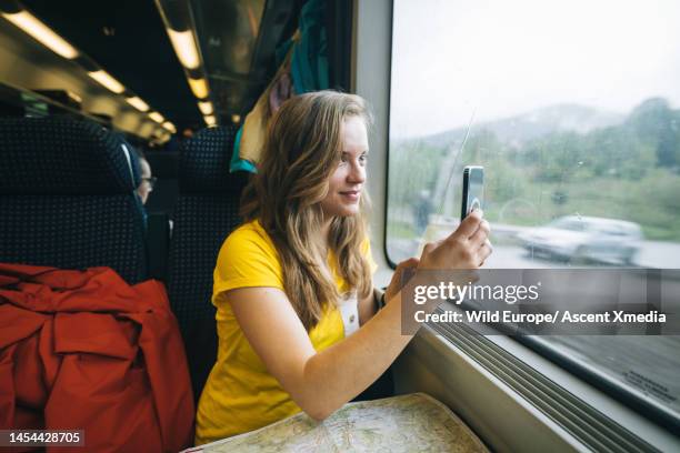 young woman takes photo with mobile phone on train - train interior stock pictures, royalty-free photos & images