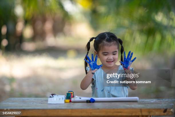 the girl paints and shows her hands - 4 girls finger painting stock pictures, royalty-free photos & images