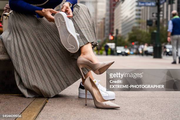 nahaufnahme der beine der frau, während sie high heels wechselt und die turnschuhe anzieht - high heels stock-fotos und bilder