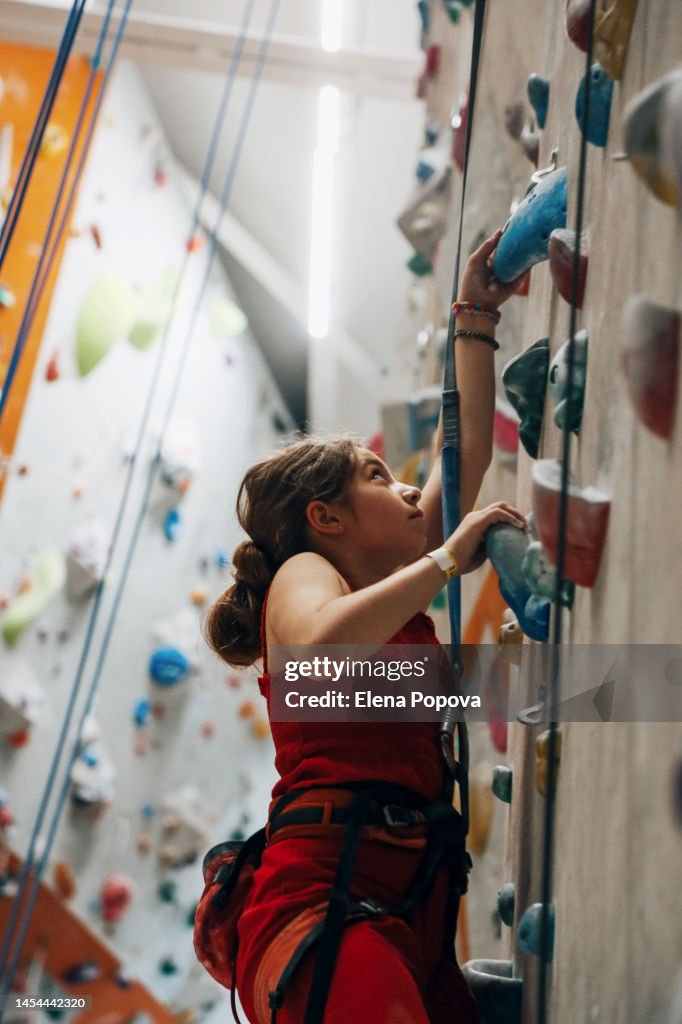 Teenage Girl Training At The Indoor Climbing Wall Gym, Profile View