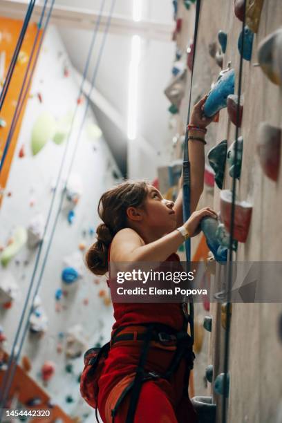 teenage girl training at the indoor climbing wall gym, profile view - rock climbing stock pictures, royalty-free photos & images