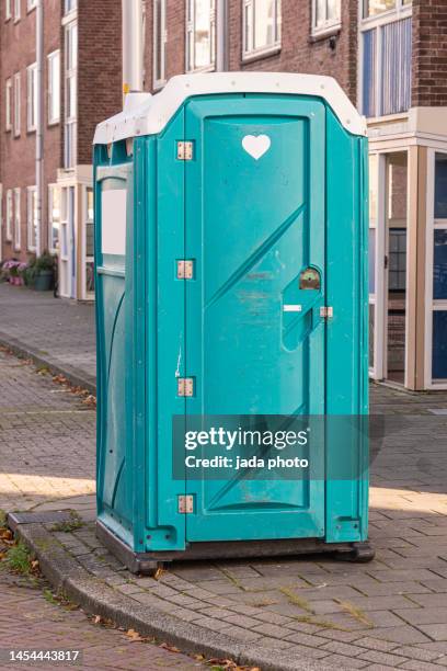 portable restroom standing on a sidewalk near an apartment building - mietklo stock-fotos und bilder