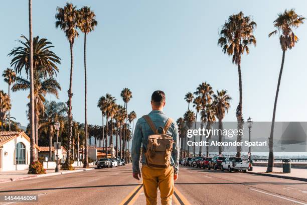 rear view of a tourist with backpack exploring santa barbara, california, usa - santa barbara foto e immagini stock