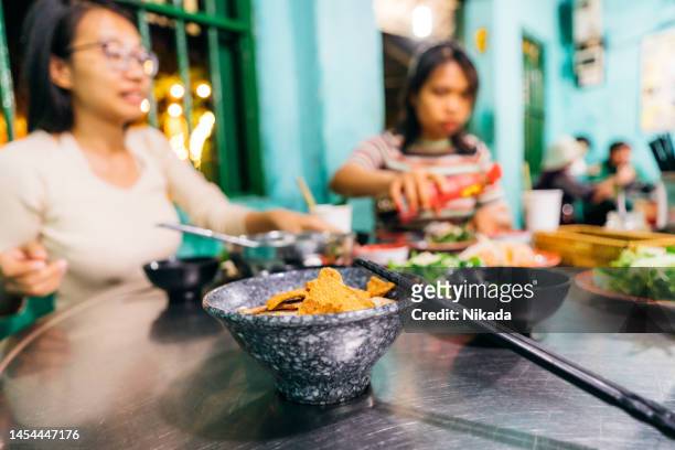 essen im straßenrestaurant in hoi an, vietnam - vietnamese street food stock-fotos und bilder
