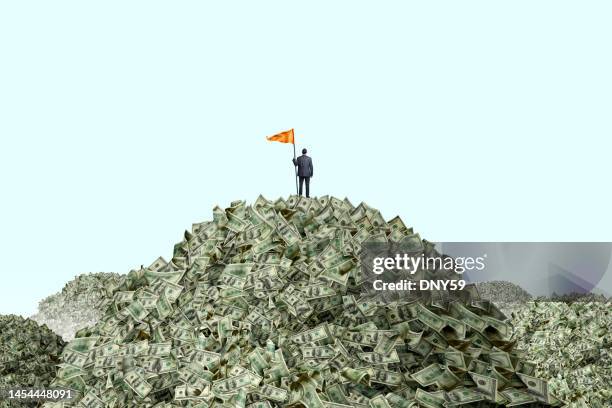 man planting flag on piles of cash - papiergeld stockfoto's en -beelden