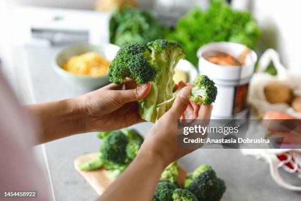 woman's hand peeling broccoli - broccoli stock pictures, royalty-free photos & images