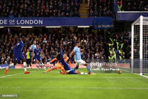 Riyad Mahrez of Manchester City scores the team's first goal whilst under pressure from Marc Cucurella of Chelsea as Kepa Arrizabalaga looks on...
