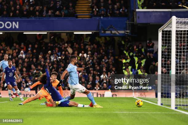 Riyad Mahrez of Manchester City scores the team's first goal whilst under pressure from Marc Cucurella of Chelsea as Kepa Arrizabalaga looks on...