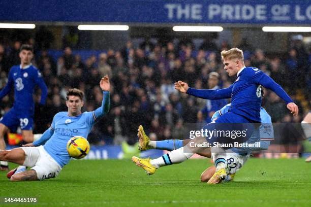 Lewis Hall of Chelsea has a shot on goal whilst under pressure from John Stones and Rico Lewis of Manchester City during the Premier League match...