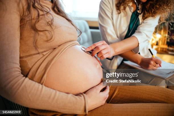 pregnant woman and doctor - listening to heartbeat stockfoto's en -beelden