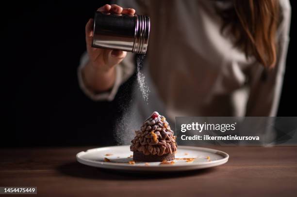 eine köchin beendet eine pinienartige kastanientarte - powdered sugar stock-fotos und bilder