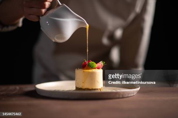 a female chef pouring sauce on a fruitcake - toetje stockfoto's en -beelden