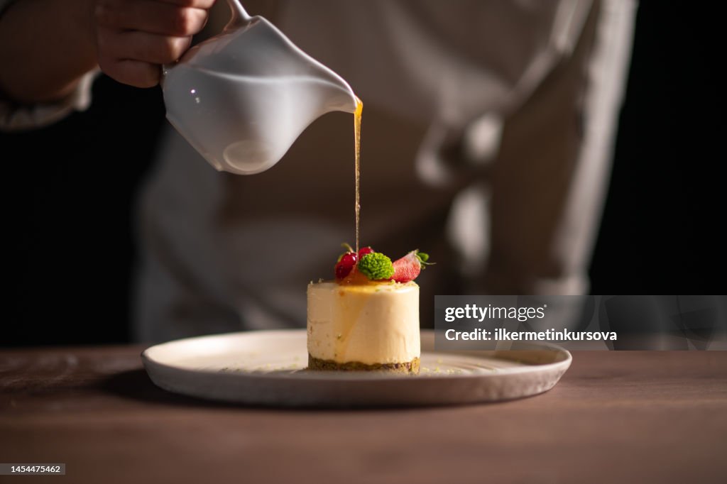 A female chef pouring sauce on a fruitcake