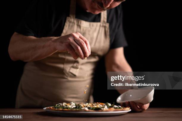 uno chef maschio che decora una pizza - gourmet foto e immagini stock