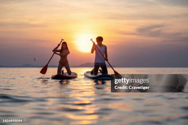 as long as you stay with me.the lovely couple kayak during sunset in the sea. - sun flare couple stockfoto's en -beelden