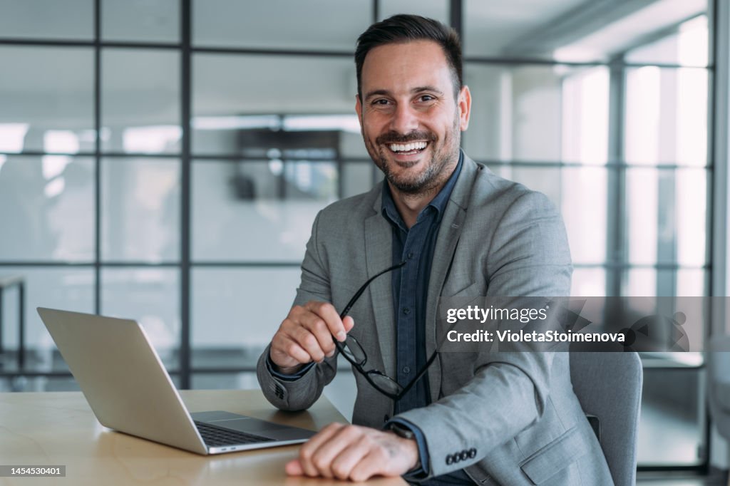 Successful businessman in modern office working on laptop.